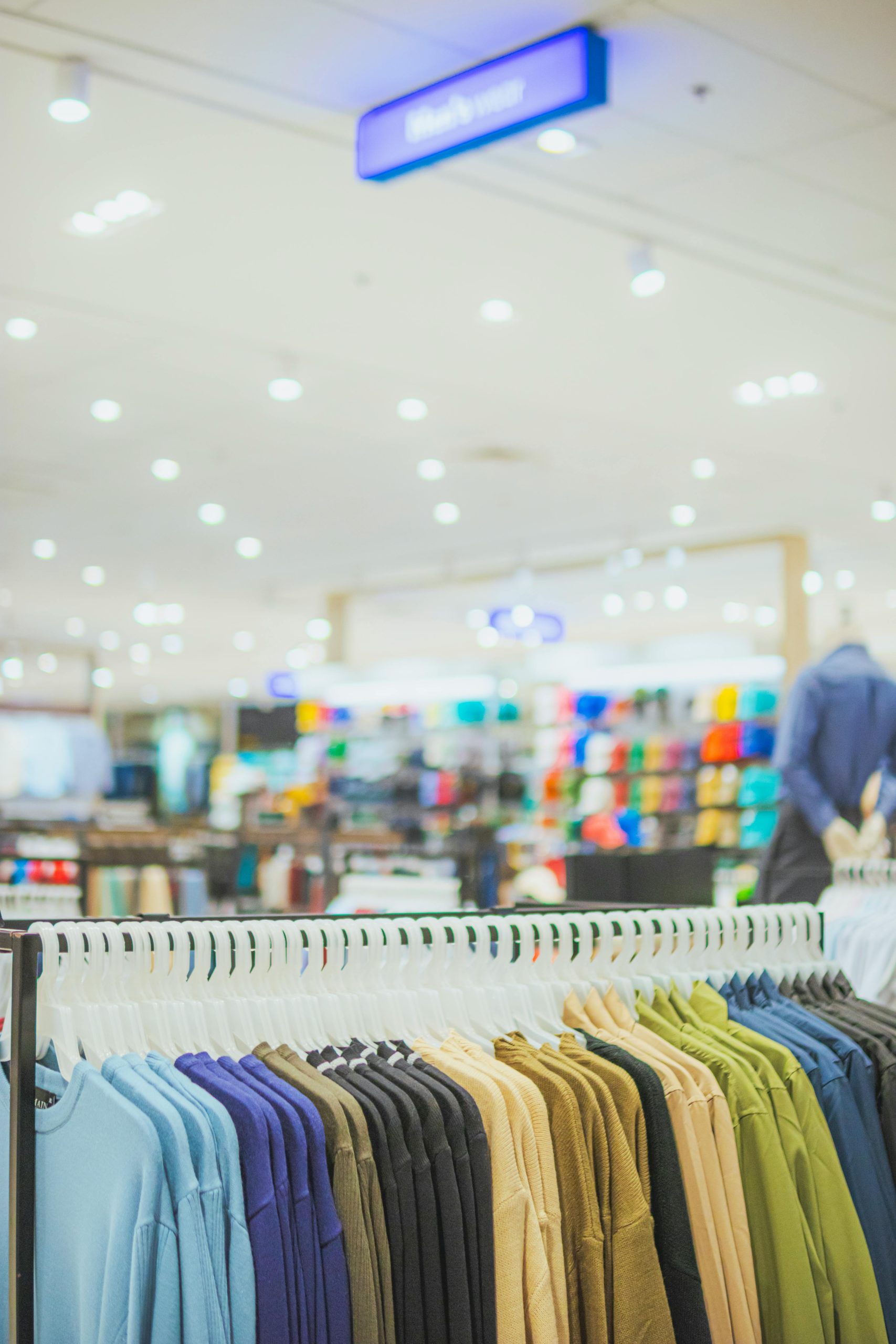 Neatly arranged clothing on hangers in a well-lit fashion store, showcasing vibrant attire.